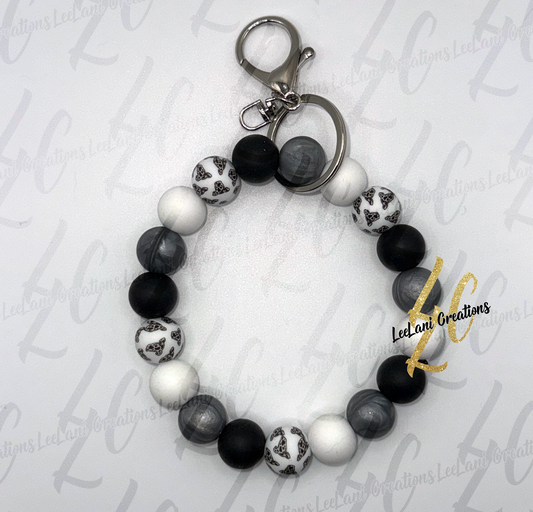Handmade cow print beaded wristlet keychain with black, white, and gray silicone beads and silver lobster claw clasp