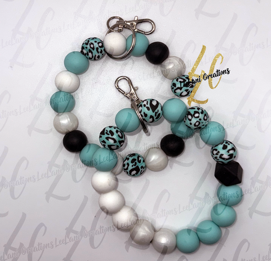 Two handmade teal leopard print silicone bead wristlet keychains shown together — round bead style and hexagon focal bead style