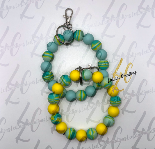 Handmade teal and yellow marbled silicone bead wristlet keychain with silver lobster claw clasp, shown in two styles